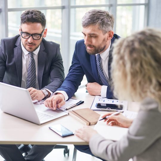 Group of concentrated financial managers sitting at spacious open plan office and working together on annual accounts